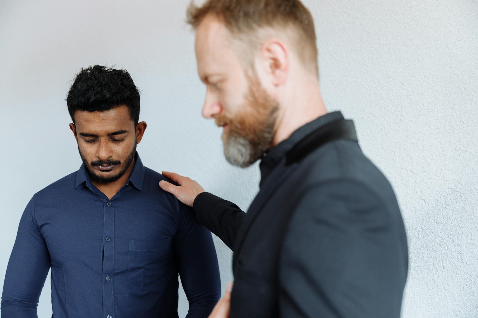Two men in an indoor setting engaged in prayer, conveying tranquility and faith.
